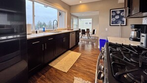 A modern kitchen with a large island, stainless steel appliances, and a view of the outdoors. - Craftsman With Breathtaking View of Downtown Seattle and Lake Washington (seattle)
