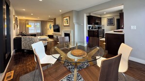 A modern living room with a glass dining table, white and brown chairs, a sofa, and a fireplace. - Craftsman With Breathtaking View of Downtown Seattle and Lake Washington (seattle)