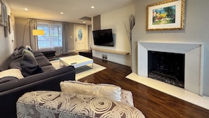 A modern living room with a sofa, a coffee table, a fireplace, and a TV mounted on the wall. - Craftsman With Breathtaking View of Downtown Seattle and Lake Washington (seattle)