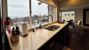 A kitchen with a large window, a sink, and a view of a balcony. - Craftsman With Breathtaking View of Downtown Seattle and Lake Washington (seattle)