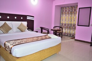 Une chambre d’hôtel avec un grand lit, un bureau, une chaise et une salle de bain avec un rideau de douche.