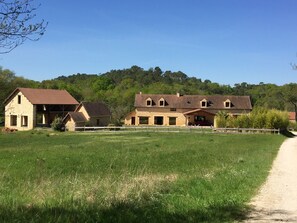 Situated in a lush green field, this traditional farmhouse offers a tranquil retreat amidst a dense forest.