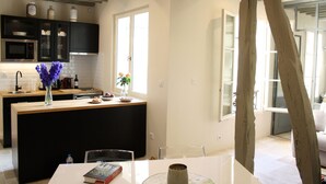 Une cuisine moderne avec des meubles de couleur noire, un îlot central en bois et un coin repas comprenant une table et des chaises.