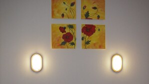 A bedroom with a wooden headboard, a bed with a quilt, two wall-mounted lights, and four paintings of flowers on the wall. - Bright, well-equipped 3-room apartment with 2 bathrooms and parking space (Orcières-merlette)
