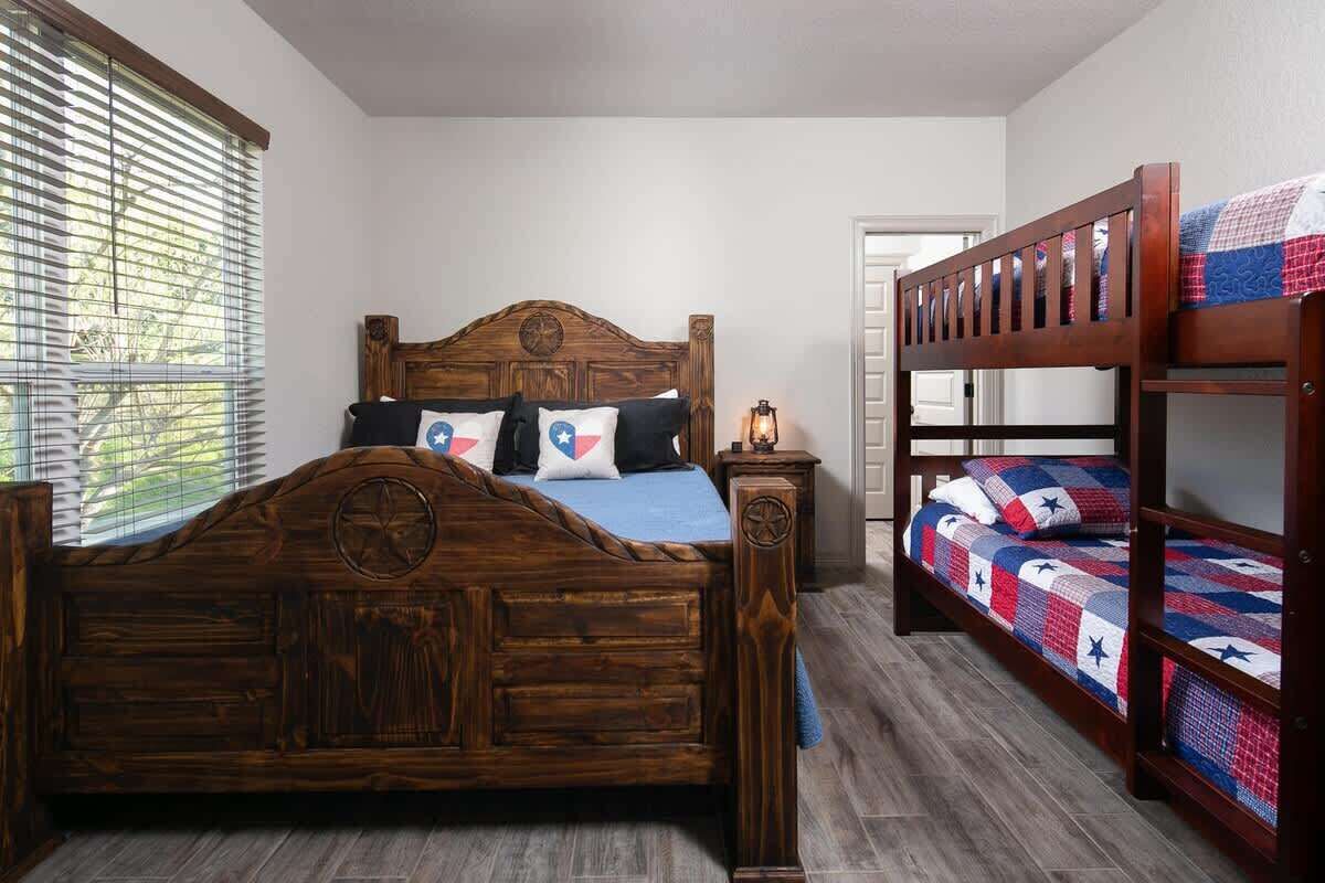 Una cama de madera con cabecera, una mesita de noche y una cama nido con colcha.