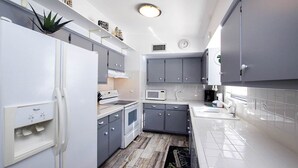 Una cocina compacta con armarios grises, un refrigerador blanco y un microondas.