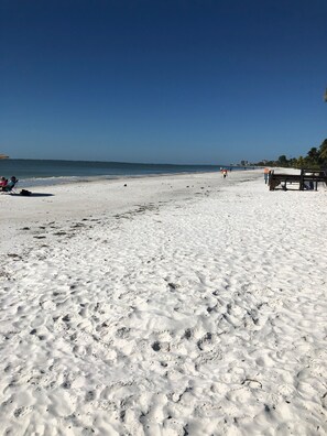 Uma extensa praia de areia com um céu azul límpido.