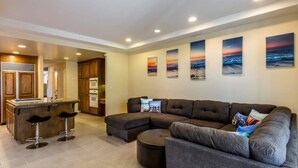 A modern living room with a sectional sofa, a bar area, and a kitchen in the background.