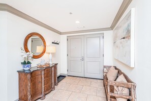Un couloir avec une armoire en bois, un miroir, une porte et un banc.