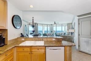 Enjoy ocean views from the spacious living area, which opens to a modern kitchen with a central island, sink, and dishwasher.