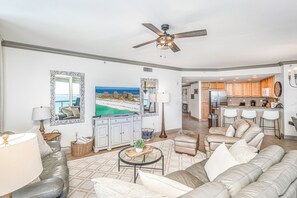 A spacious living room with a large sofa, a coffee table, and a view of the ocean through a window. - P2-0901 3 Bedroom * Perfect For Large Families (Pensacola Beach)