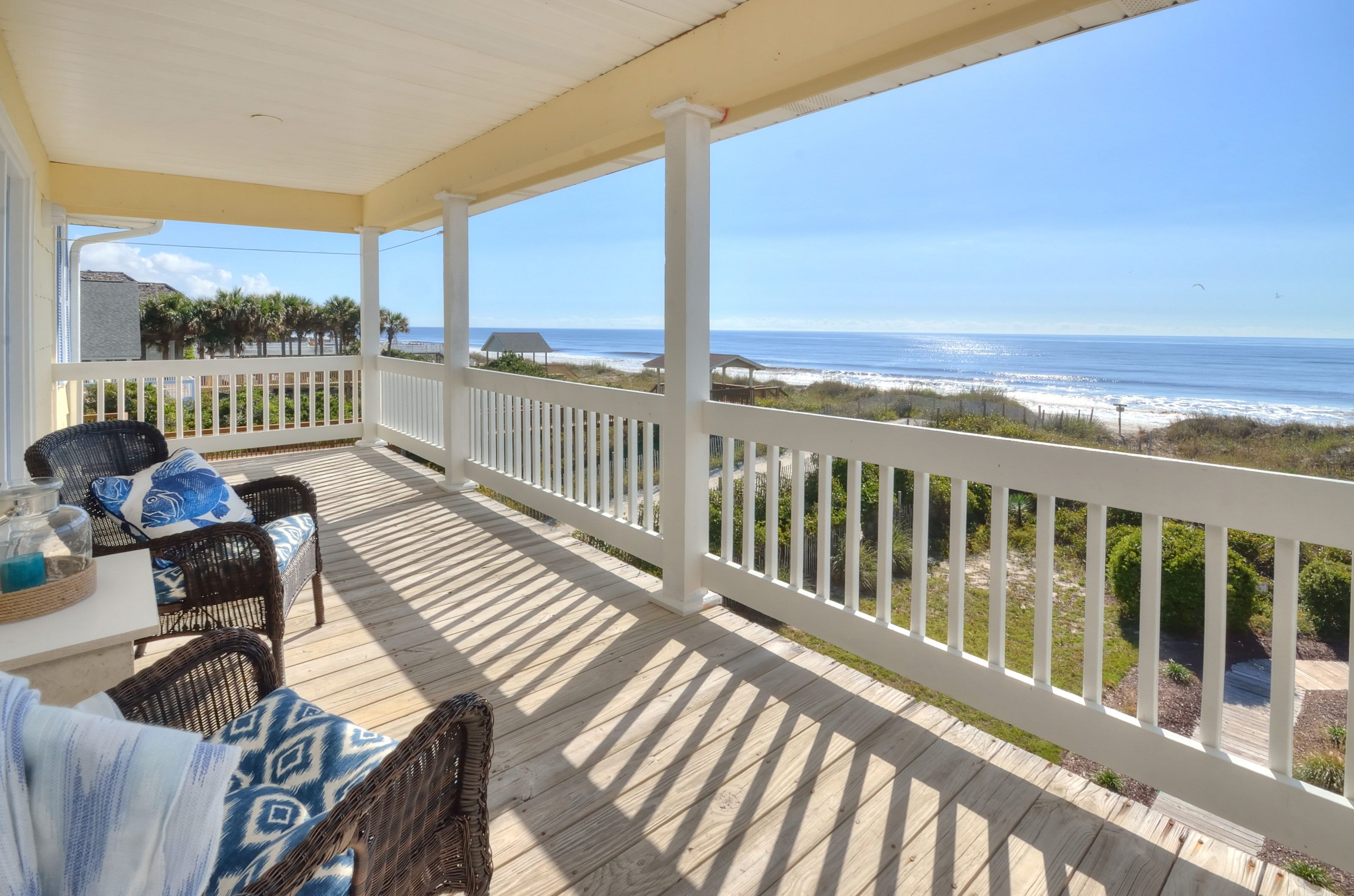 Eine überdachte Terrasse mit Korbmöbeln und Blick auf den Strand.