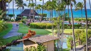 A golf course with a view of the ocean, palm trees, and a pool area. - GORGEOUS OCEANFRONT PENTHOUSE  (Lahaina)