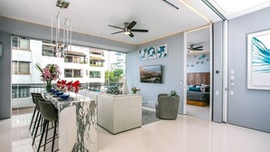A modern kitchen with a marble countertop, a dining area with chairs, and a view of neighboring buildings. - Pier 57 Luxury Escape 2BR, PV’s Best Rooftop! (Puerto Vallarta)