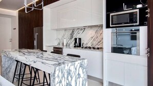 A modern kitchen with a marble island, white cabinetry, and stainless steel appliances. - Pier 57 Luxury Escape 2BR, PV’s Best Rooftop! (Puerto Vallarta)