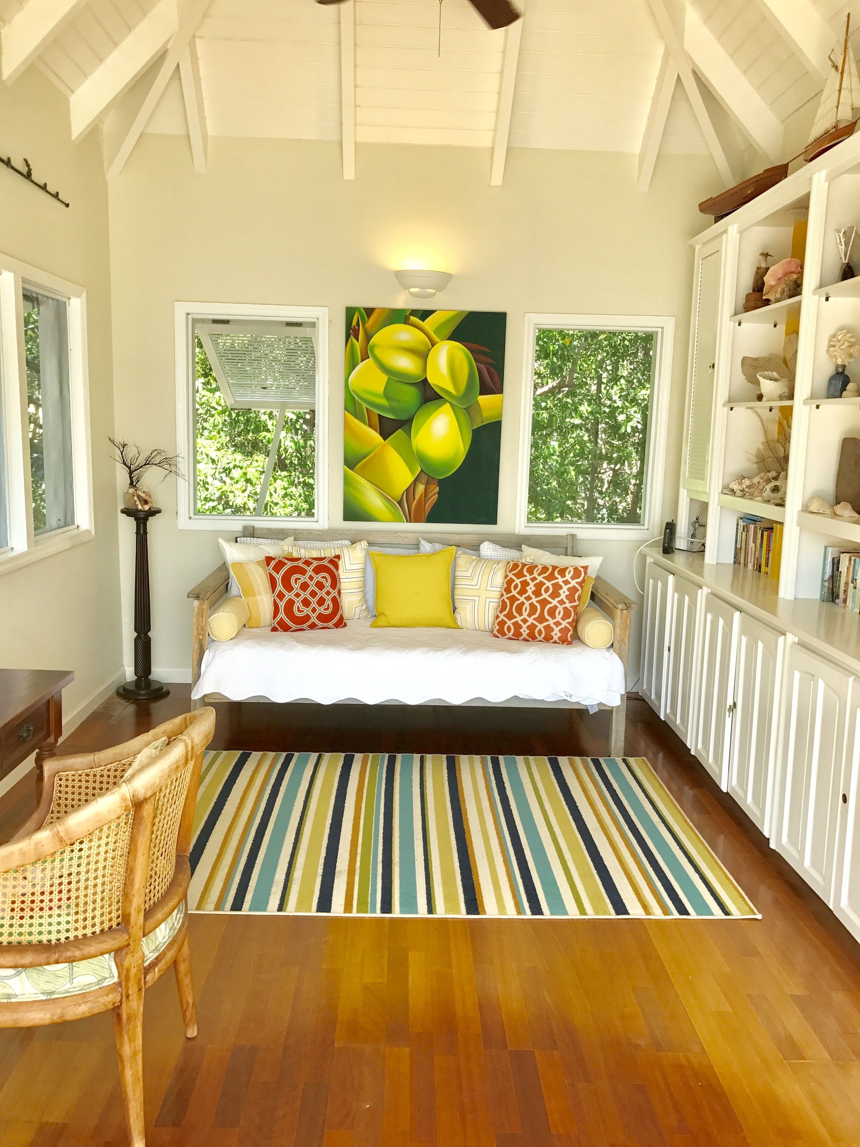 A cozy bedroom with a bed, a striped rug, and a bookshelf.