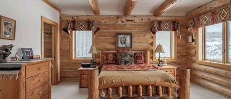 Une chambre située dans une cabane en rondins, avec un lit, une commode en bois et un ventilateur de plafond.