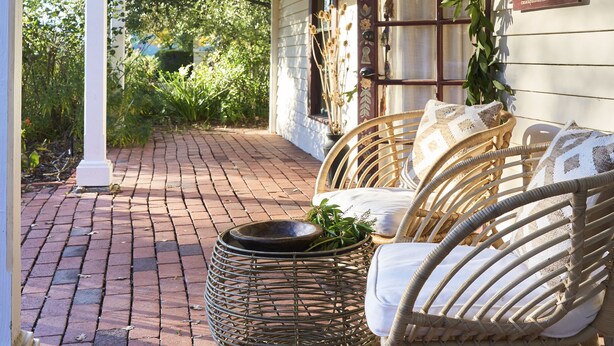 A covered porch with wicker furniture and a woven basket.