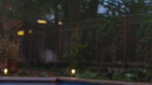 A poolside area with a candle, wooden deck, and a view of the pool.