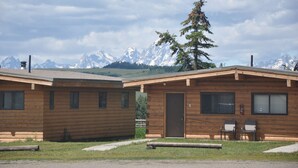 A wooden cabin with a door and windows, two chairs outside, and a mountain backdrop. - Cute 2/1 Cabin With Full Kitchen And Teton Views (Moran)