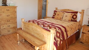 A wooden bed with patterned bedding, a wooden bench, a wooden dresser, and a wooden nightstand. - Cute 2/1 Cabin With Full Kitchen And Teton Views (Moran)
