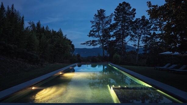 A swimming pool with a view of trees and mountains in the background.