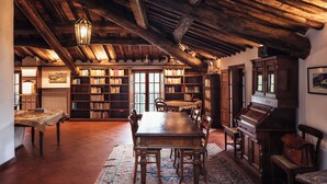 A spacious library with wooden bookshelves, a large wooden table, and a high ceiling with exposed beams.