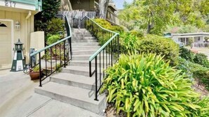 A residential property with a staircase leading to a covered porch, surrounded by lush greenery and a clear sky. - Rio Del Mar Aptos-two blocks to the Sand, Ocean, Store, Restaurant, Coffee shop (Aptos)