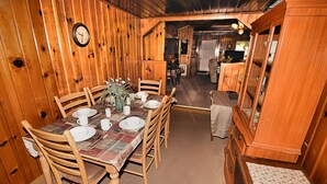 Ein Esszimmer mit Holzboden, einem Tisch für sechs Personen, Stühlen und einer Wanduhr.
