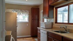 Una cocina compacta con armarios de madera, un refrigerador, un microondas y un lavamanos.