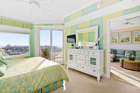 Un dormitorio con una cama grande, un aparador, un televisor y vistas de la ciudad.