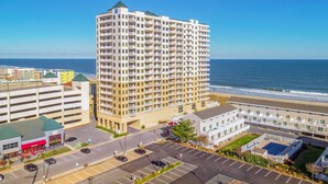 Un hotel de gran altura con varios balcones, un estacionamiento y vista a la playa.