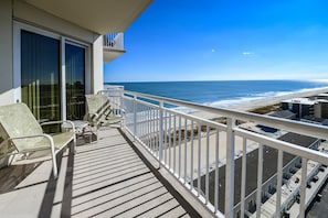 Un balcone con vista sull'oceano, arredato con sedie e un tavolo.