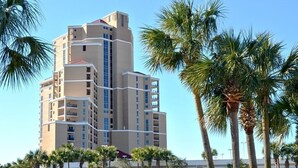 Un hôtel à plusieurs étages au design moderne, doté d’une cour intérieure avec un bassin et des palmiers.
