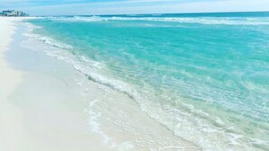 Une plage à l’eau turquoise et limpide, bordée d’un rivage sablonneux.