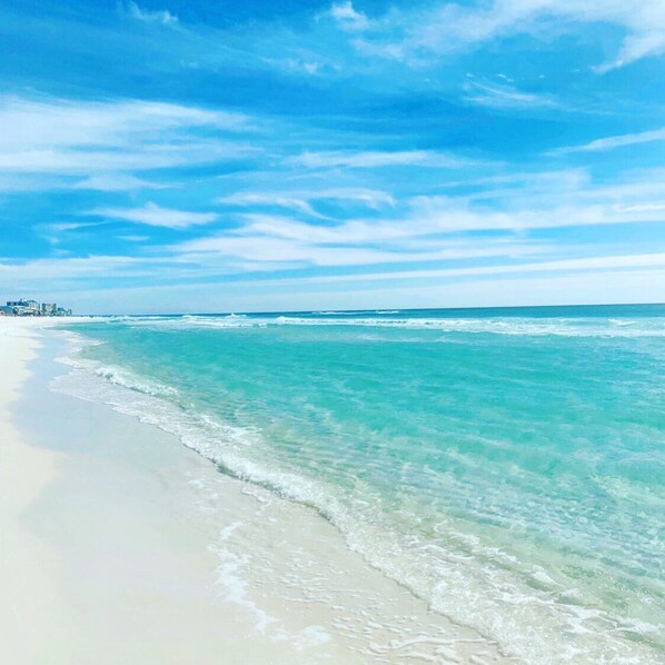 Une plage à l’eau turquoise et limpide, bordée d’un rivage sablonneux.