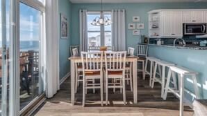 Una cocina moderna con armarios blancos, un ventanal grande y un comedor con sillas y mesa de madera.