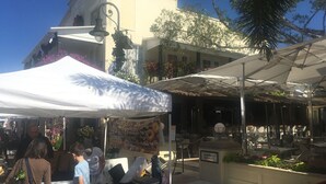 Ein Café im Freien mit weißem Baldachin, Tischen und Stühlen.