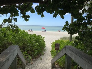 A beach path leading to a sandy beach with people relaxing under umbrellas. - Romance on 3rd St South Old Naples (Naples)
