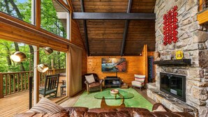 A cozy living room with a stone fireplace, leather sofa, and a large TV screen. - Honey Bear– Unique A-Frame Chalet w/ Mt LeConte View & Hot Tub in Gatlinburg (Gatlinburg)