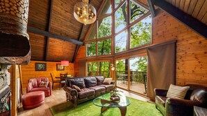 A cozy wooden interior with a leather sofa, a glass coffee table, and a stone fireplace. - Honey Bear– Unique A-Frame Chalet w/ Mt LeConte View & Hot Tub in Gatlinburg (Gatlinburg)
