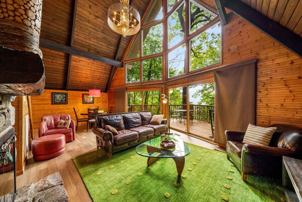 A cozy wooden interior with a leather sofa, a glass coffee table, and a stone fireplace.