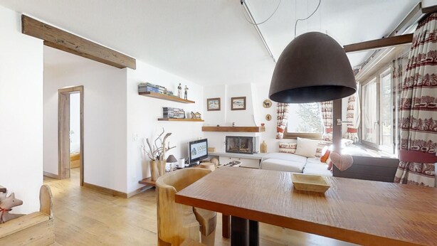 Ein modernes Wohnzimmer mit einem Holzespeisetisch, einem Kamin und einem großen Fenster mit Vorhängen.