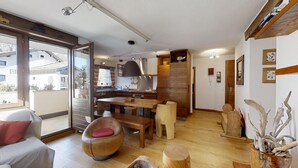 Ein modernes Wohnzimmer mit großem Fenster, Essbereich und Küche.