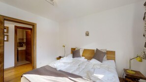 Ein Schlafzimmer mit einem hölzernen Bett, weißer Bettwäsche, einer Nachttischlampe und einem Holzschrank.