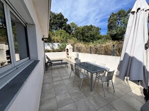 An outdoor patio with a table and chairs, a covered area, and a view of the surrounding landscape.