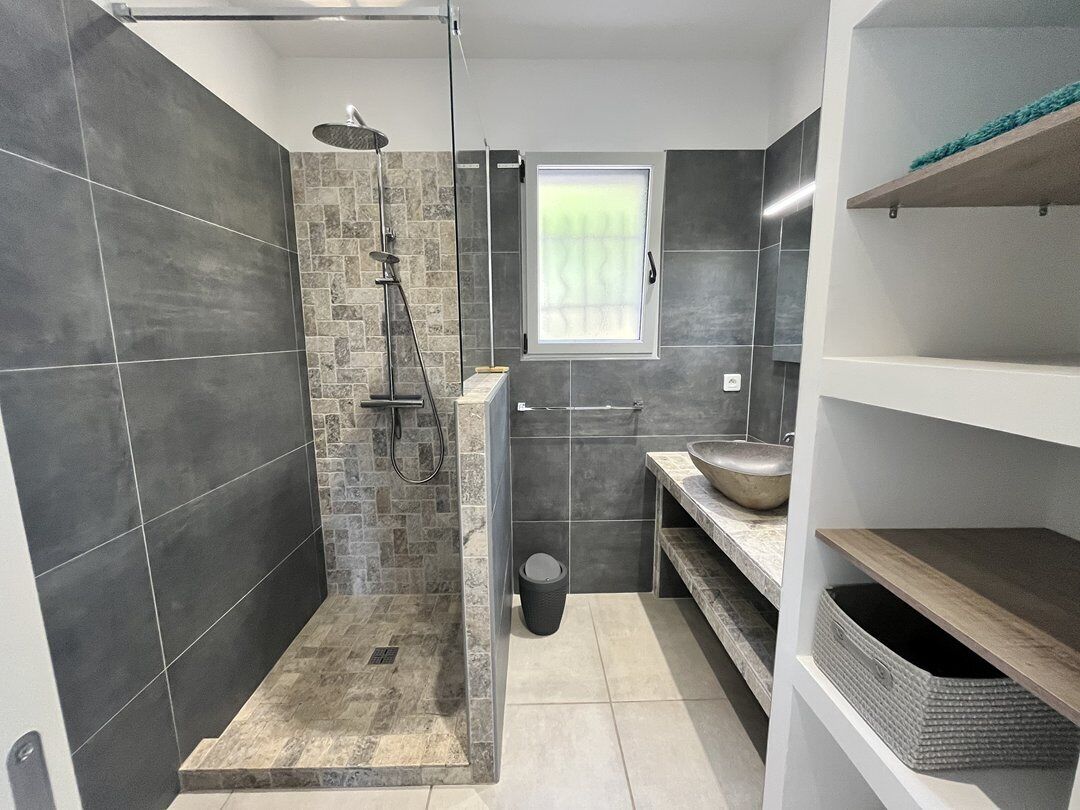 Une salle de bain moderne avec une douche, un lavabo et une fenêtre.