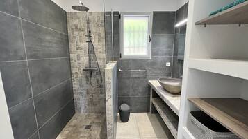 Une salle de bain moderne avec une douche, un lavabo et une fenêtre.