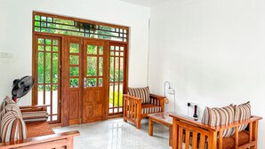 A room with a wooden door, a fan, a sofa, a table, and a power outlet. - Heaven Hills Guest House (Maskeliya)