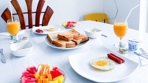 A breakfast table with toast, eggs, sausages, and fruit. - Heaven Hills Guest House (Maskeliya)